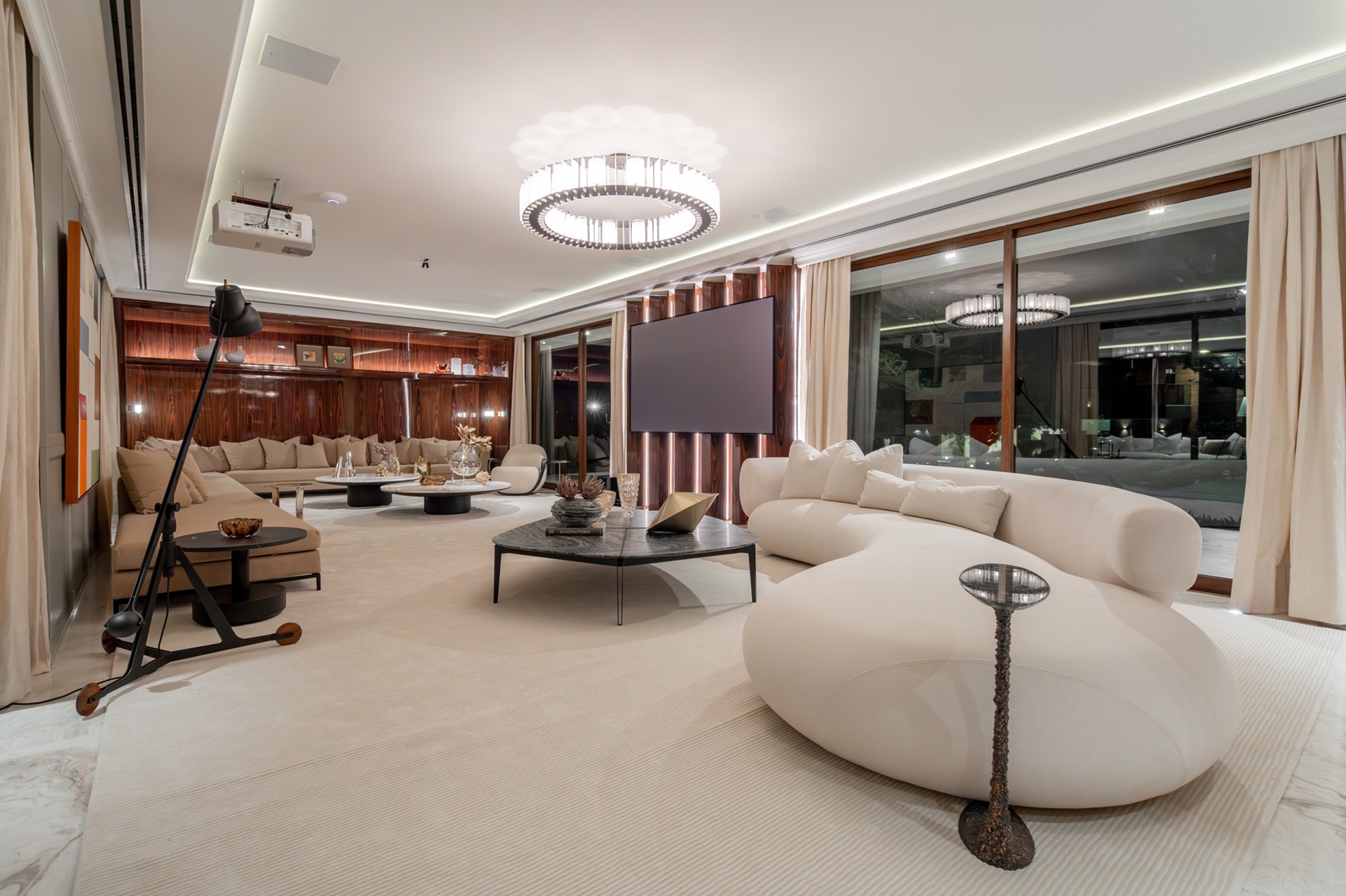 Sala de estar e living integrados, com móveis claros e tapete amplo
