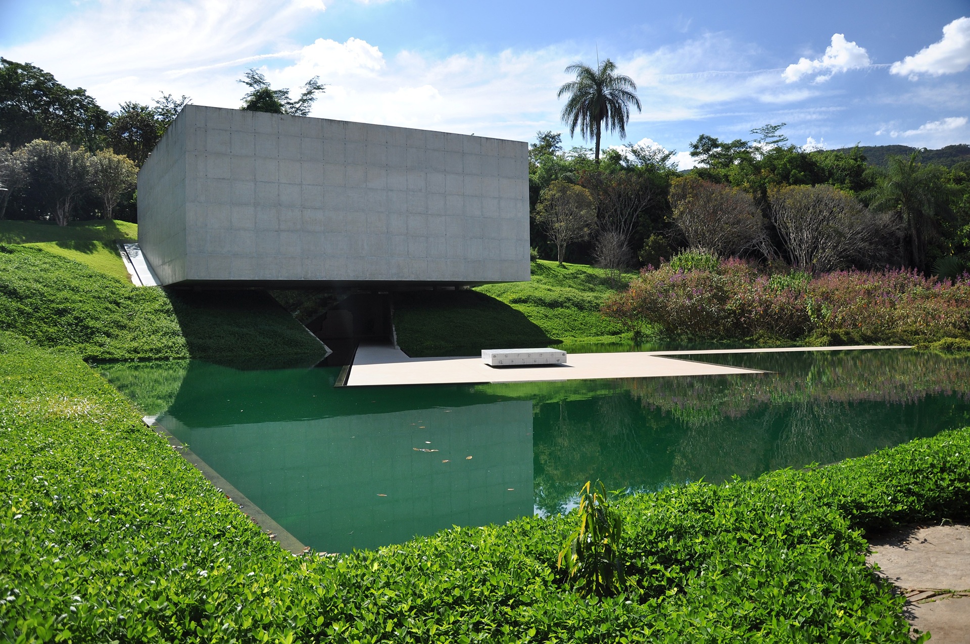 Parte externa no pavilhão de Adriana Varejão em Inhotim, com lago na frente e paisagismo abundante