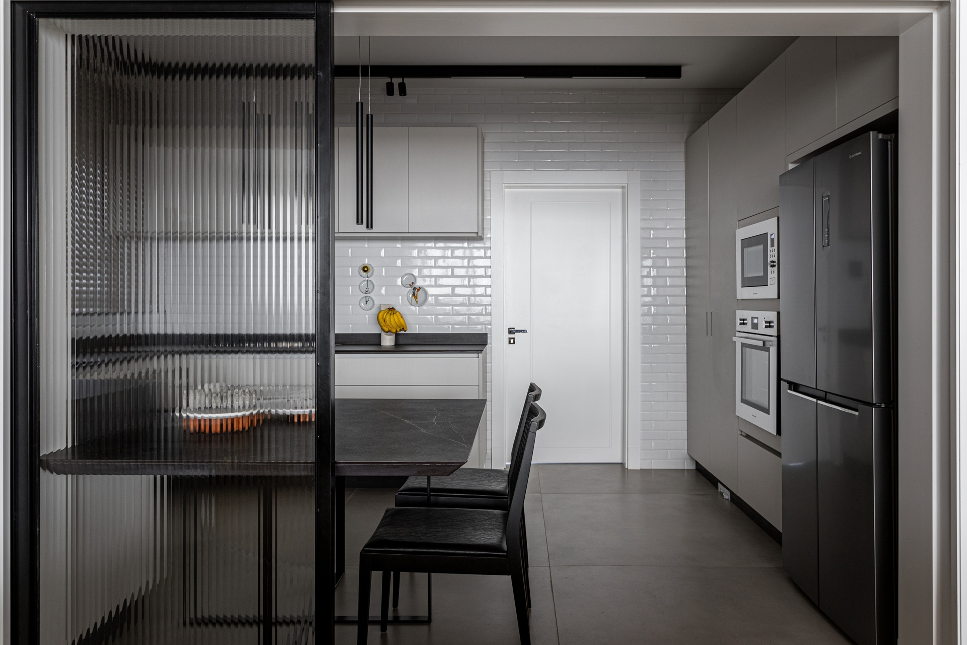 Cozinha em tons de preto e branco, com parede de azulejo de metrô branco ao fundo