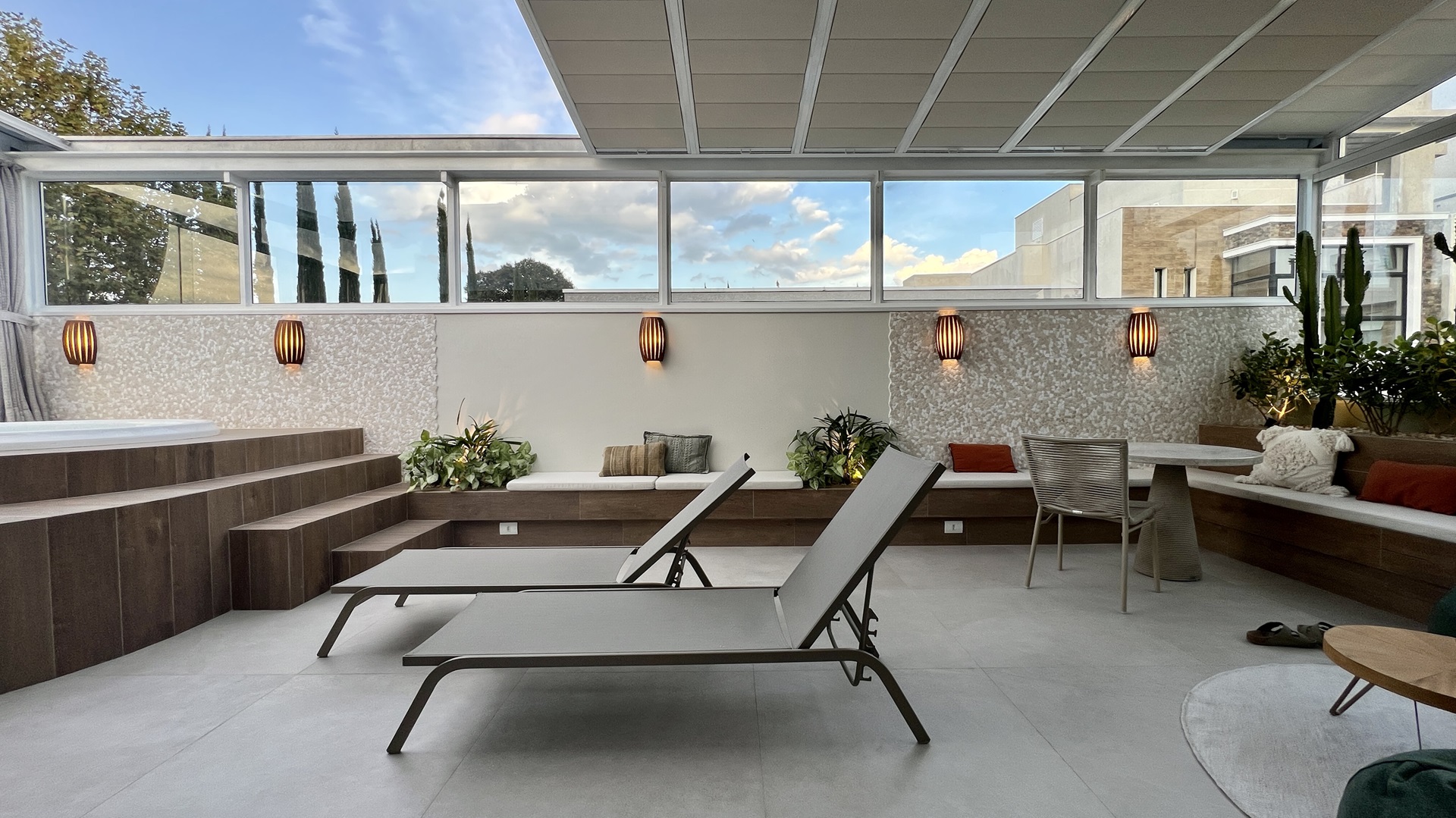 Área externa coberta com piso cinza e deck de piscina com porcelanato amadeirado