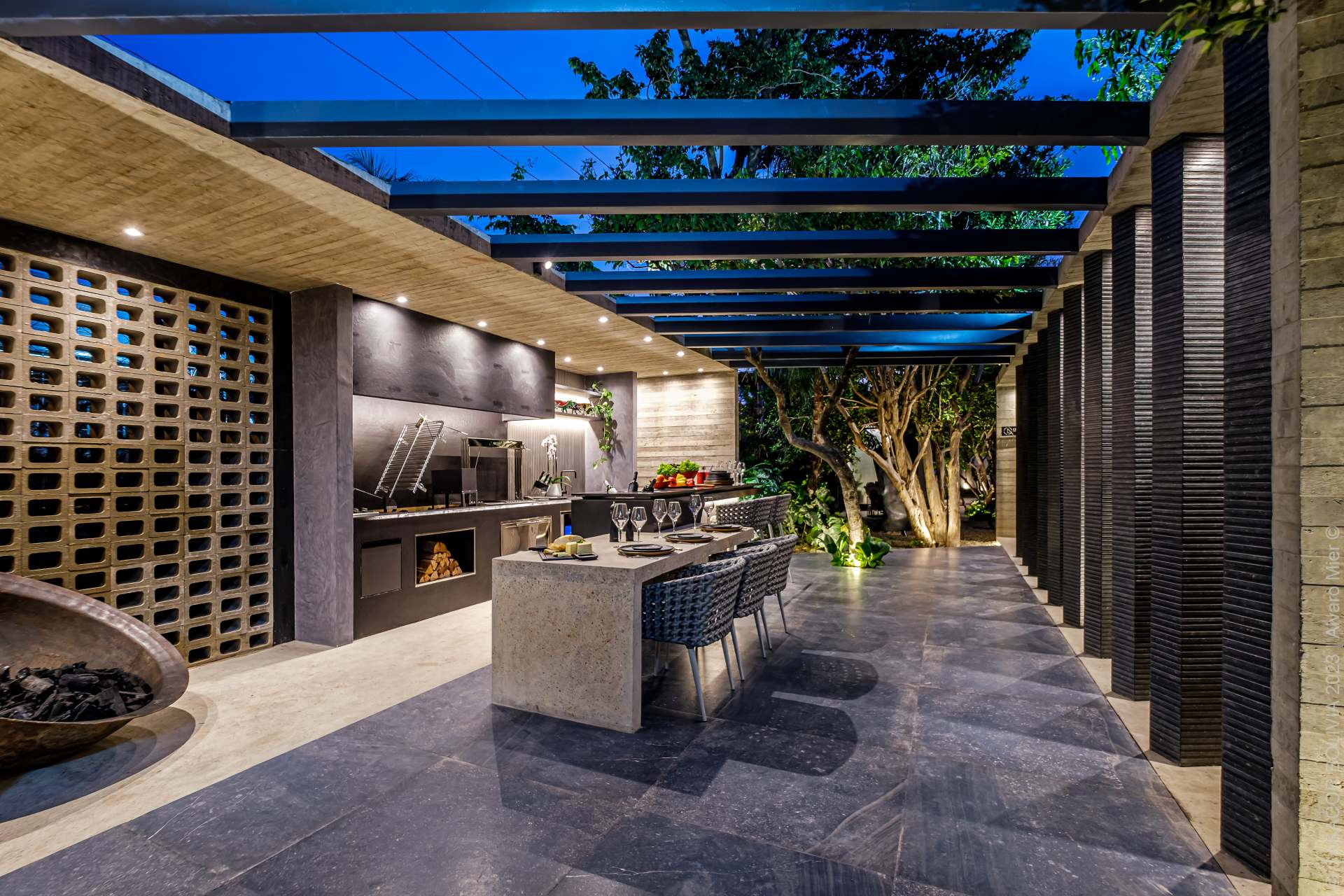Área externa com churrasqueira revestida com porcelanato que reproduz concreto