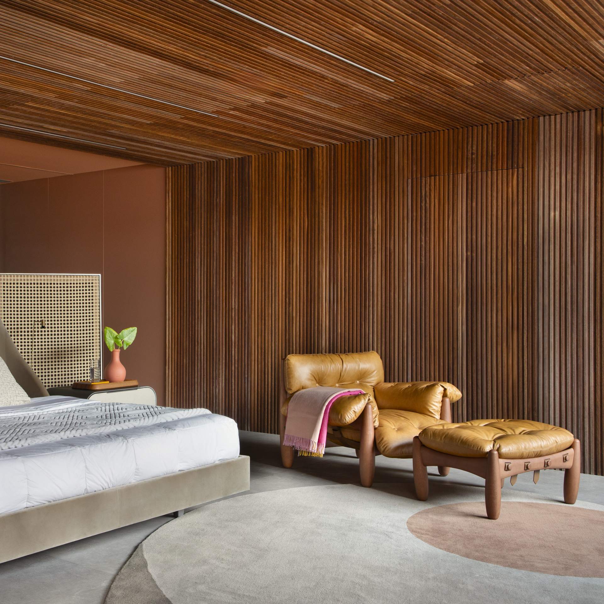 Quarto com poltrona e painel de madeira