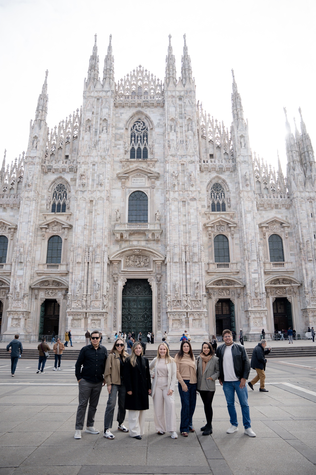 Grupo de sete pessoas em frente ao Duomo de Milão