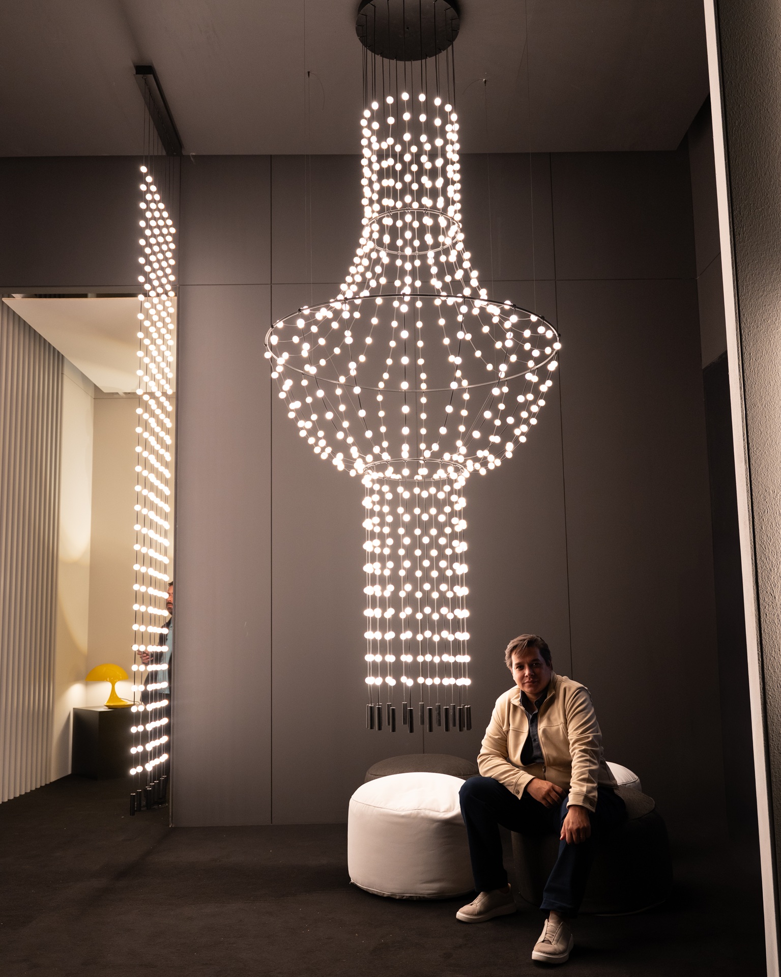 Homem sentado ao lado de lustre gigante