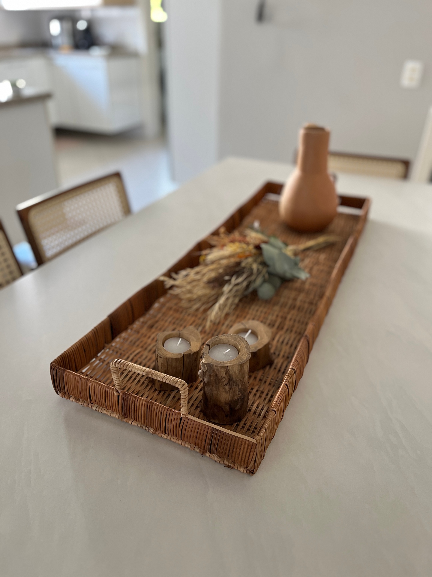 Uma bandeja de vime com velas e um vaso
