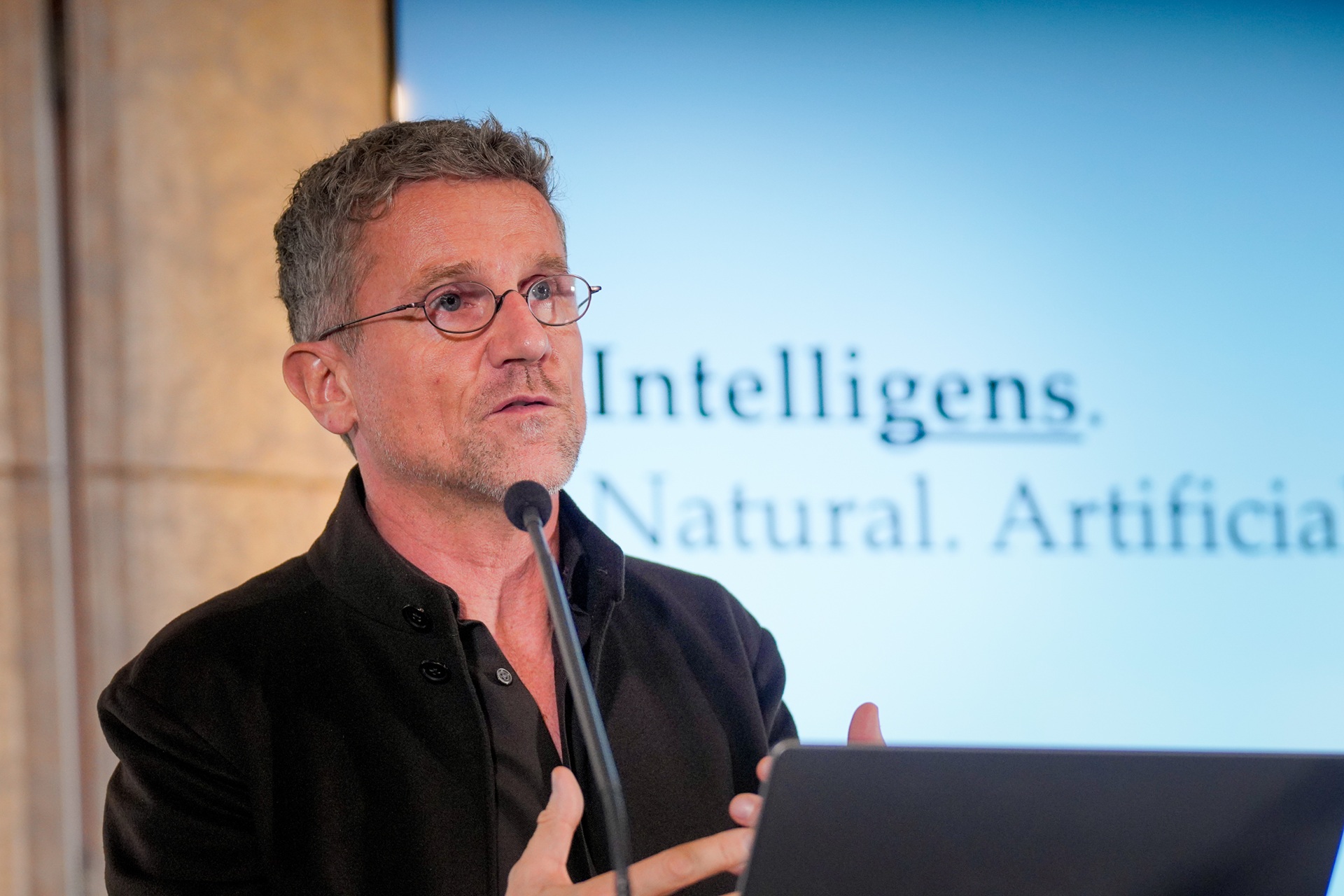 Carlo Ratti falando em microfone em frente a painel de apresentação