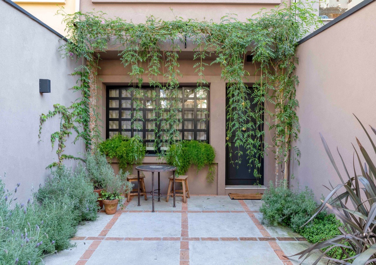 Casa geminada, com fachada em tom terroso e com muitas plantas