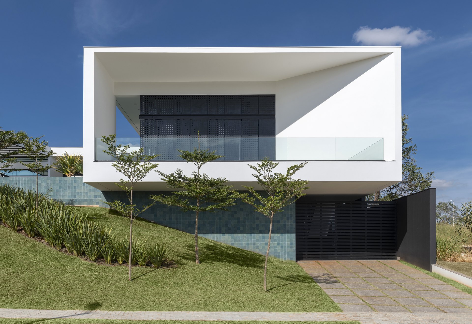 Fachada em linhas retas e cores neutras com jardim à frente