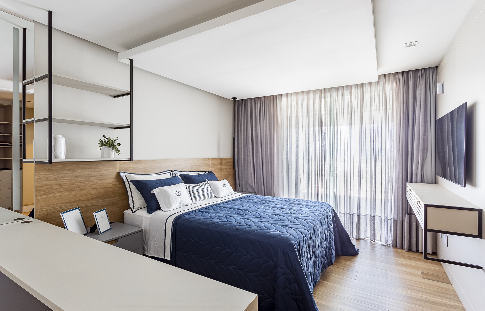 Quarto com piso e cabeceira amadeirados e cama de casal