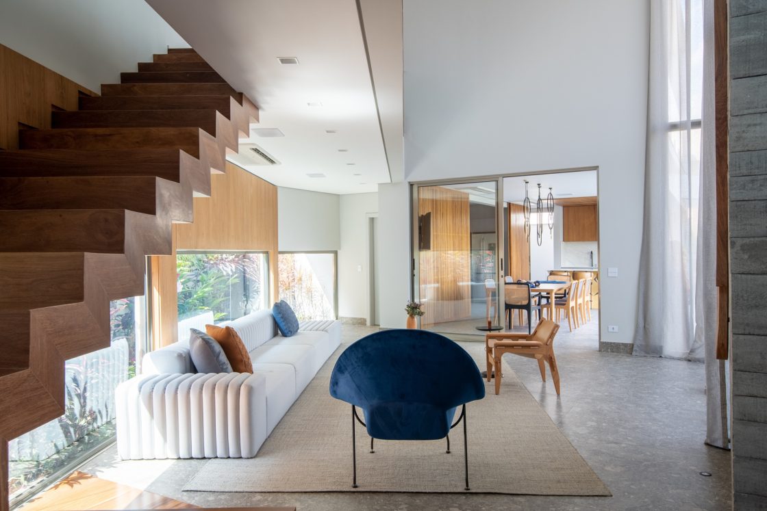 Sala em tons neutros com integração com sala de jantar por meio de porta de vidro