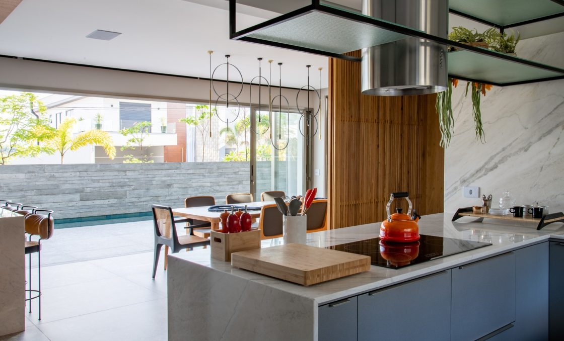 Ilha de cozinha com visão para a área externa através de porta de vidro