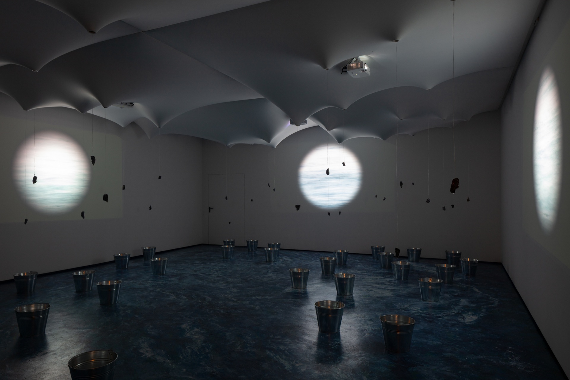 Ambiente escuro com projeção na parede no Pavilhão do Uruguai na Bienal de Veneza 2025