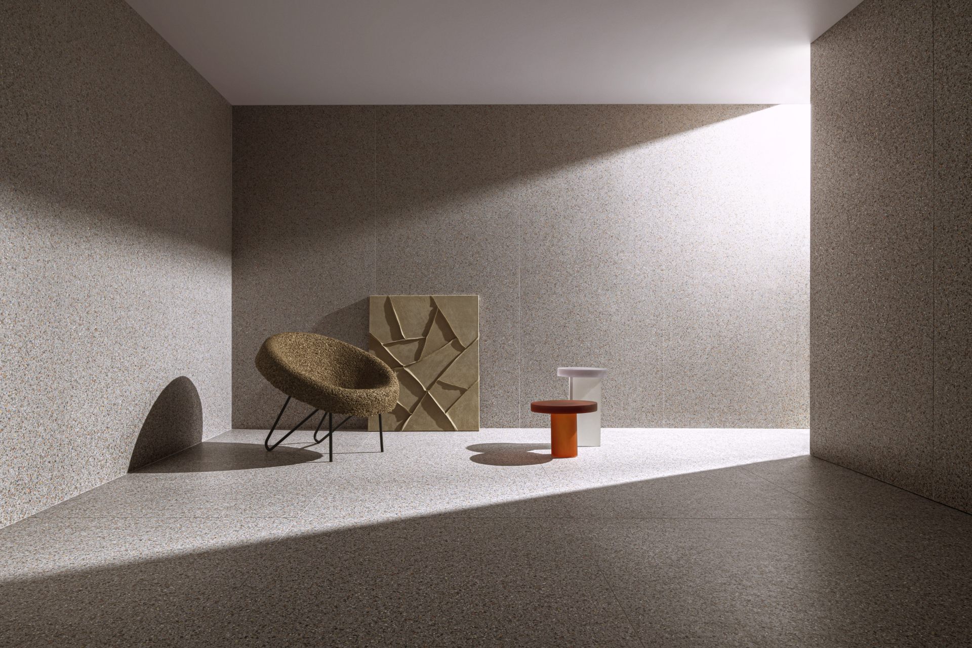 Ambiente com piso e parede revestidos com o mesmo produto. Há uma poltrona, mesinhas e um quadro