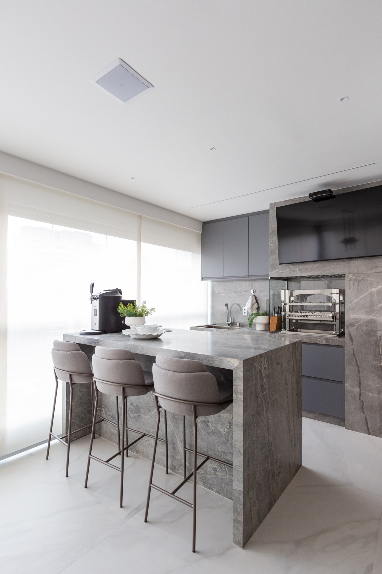 Área gourmet com ilha em porcelanato que recria mármore cinza