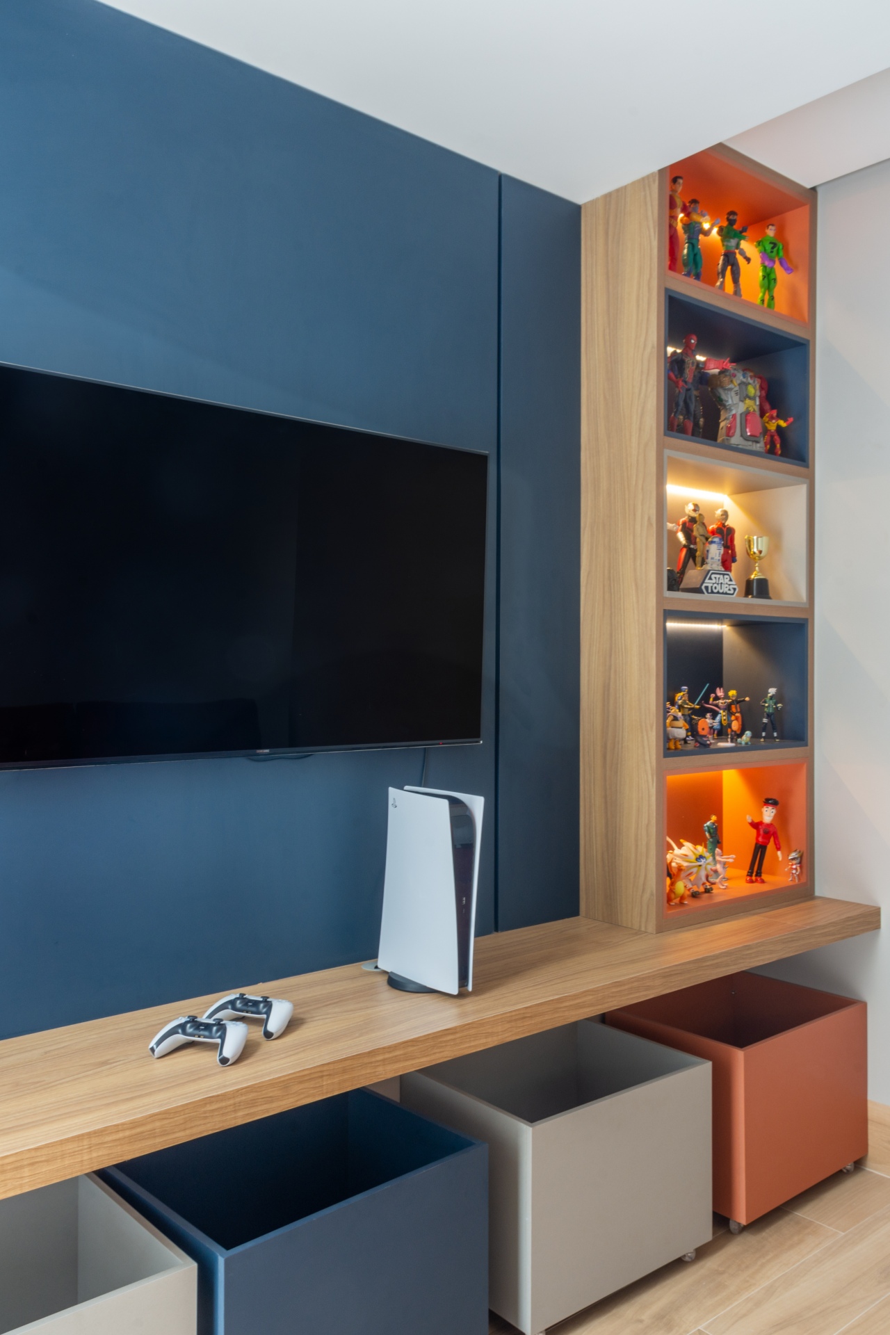 Sala colorida, possivelmente de brinquedos, com consolde de videogame e action figures