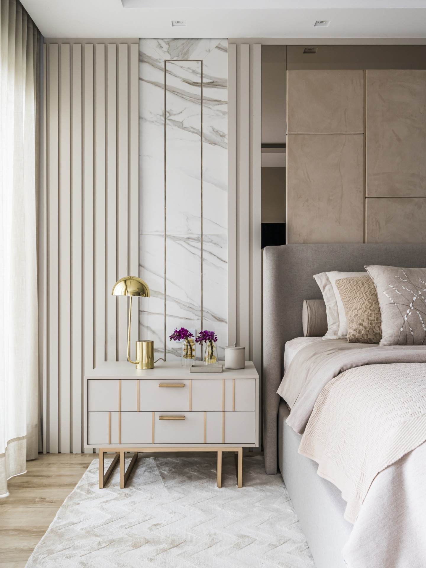 Quarto em tons neutros claros, com mesa de cabeceira e cama