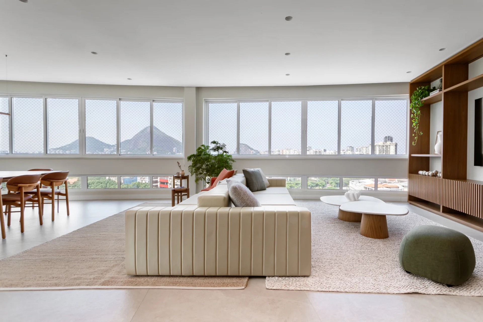 Living com ambiente integrado em cores neutras e dois janelões com vista para a paisagem do rio de janeiro