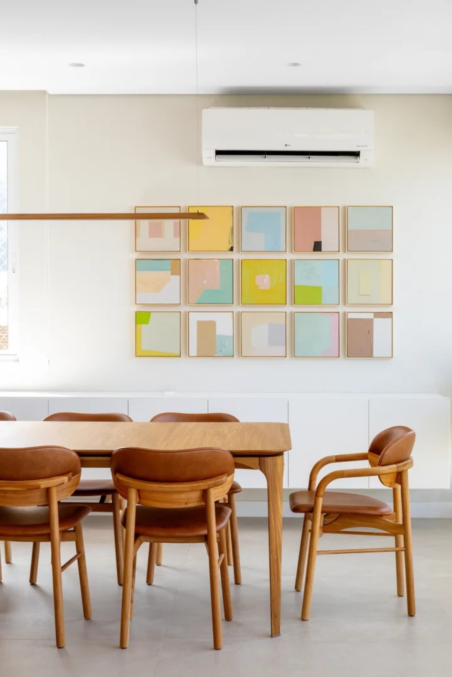 Mesa de jantar com luminária e quadro na parede em tons pastel