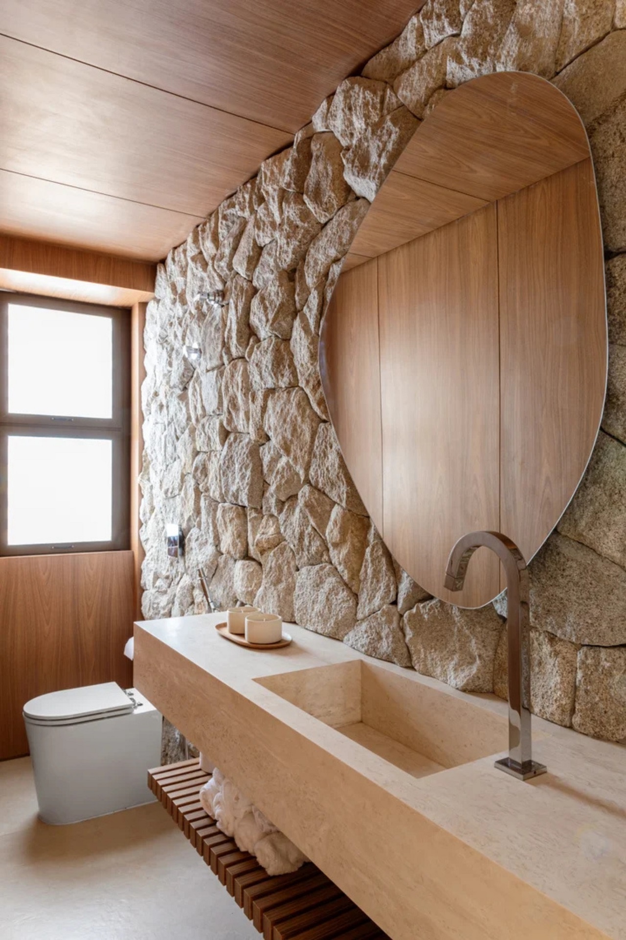 Lavabo com parede em pedras naturais e acabamentos em madeira