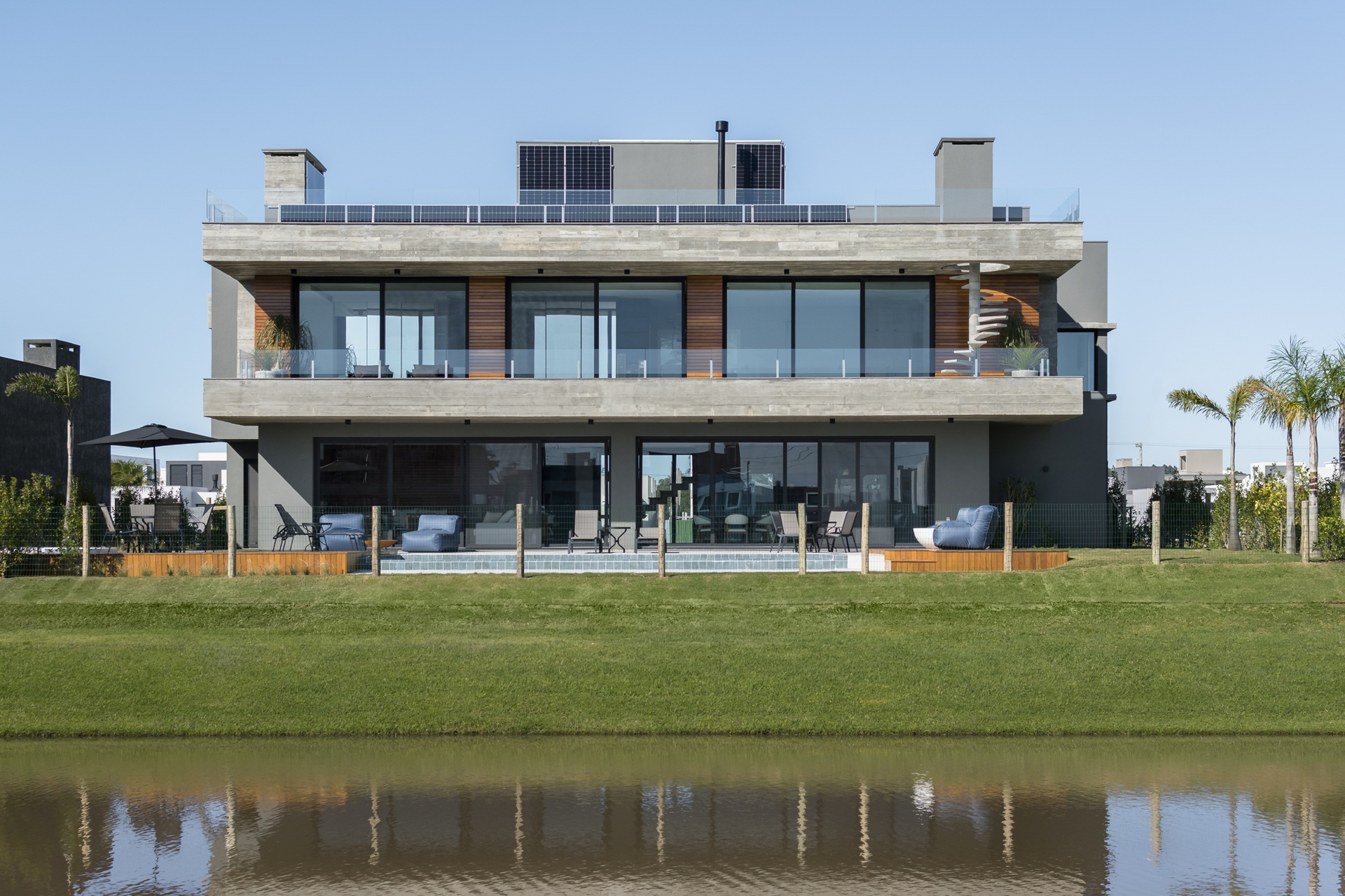 Fachada de casa de dois pavimentos com piscina em frente a um lago