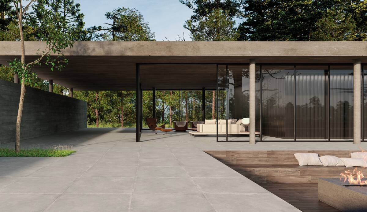 Residência contemporânea com fachada de vidro e estrutura em concreto. Em destaque, um fire pit retangular em área rebaixada com piso de madeira e almofadas