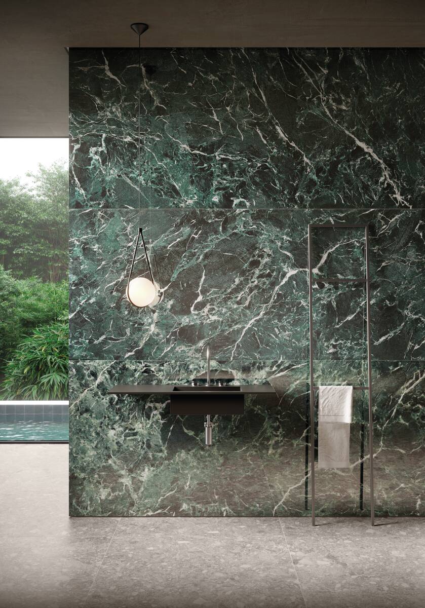 Parede revestida com porcelanato Verde Alpi e bancada de banheiro em frente