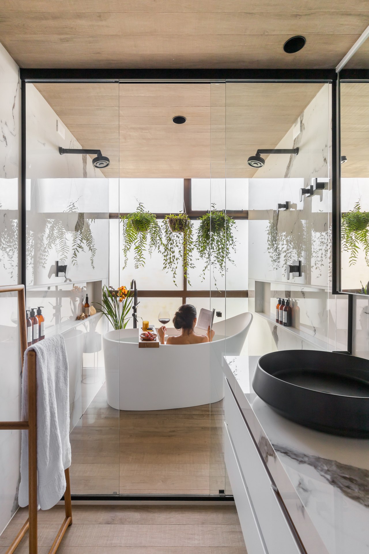 Mulher vista de costas na banheira desfruta de momento relaxante em banheiro com ótima iluminação natural e atmosfera de spa