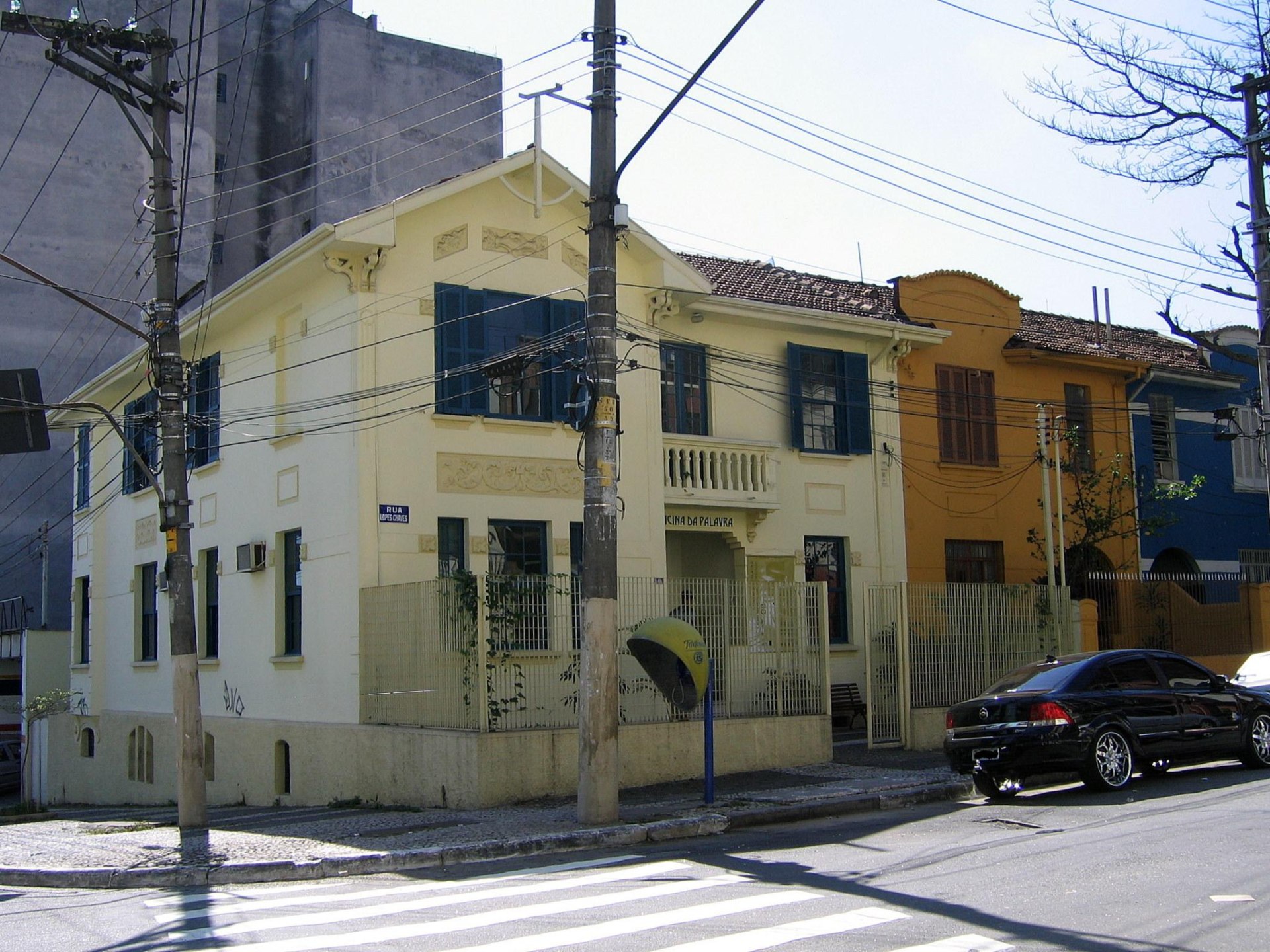 Sobrado de esquina, pintado na cor amarelo-claro e com ajanelas pintadas de azul-marinho