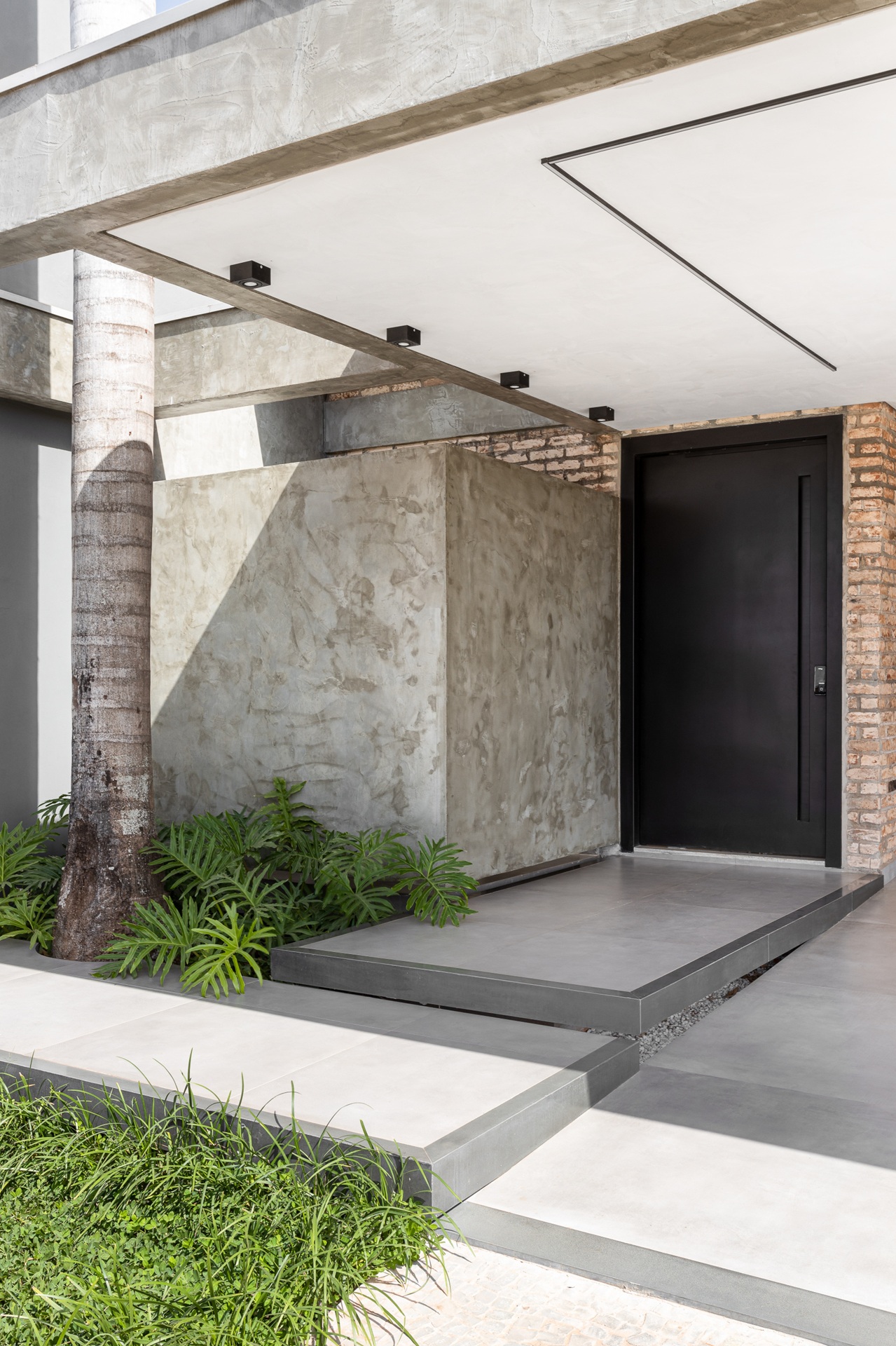 Painel em concreto aparente ao lado de porta de entrada de casa contemporânea