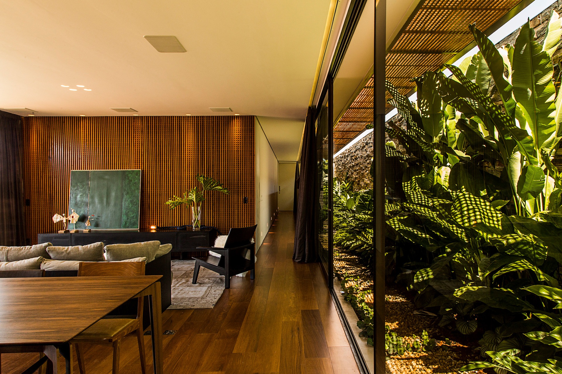 Sala com revestimento amadeirado e jardim de inverno