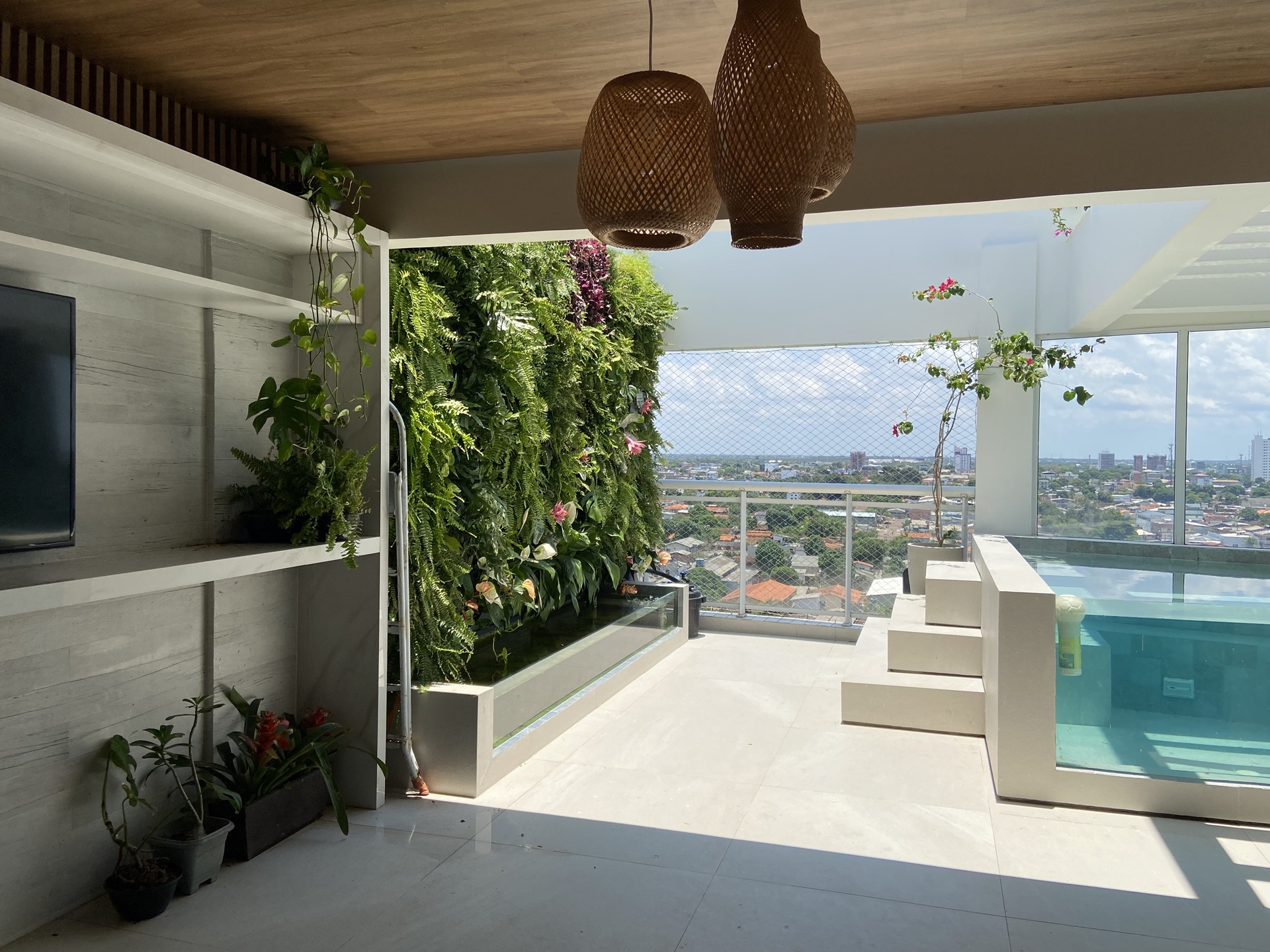 Cobertura de apartamento com jardim vertical e lago com peixes em frente à piscina