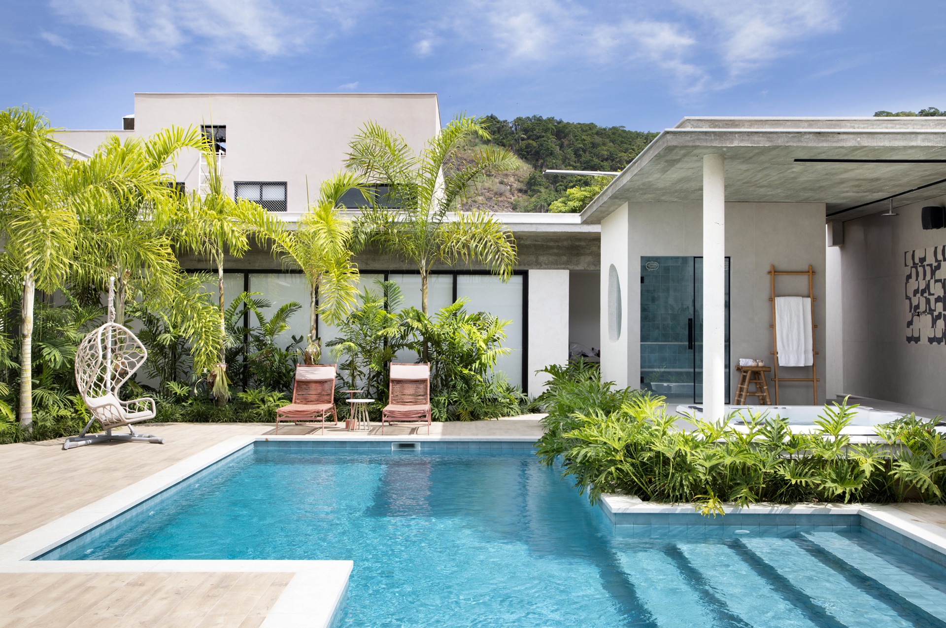 Quintal com piscina e plantas no entorno dos muros e da piscina