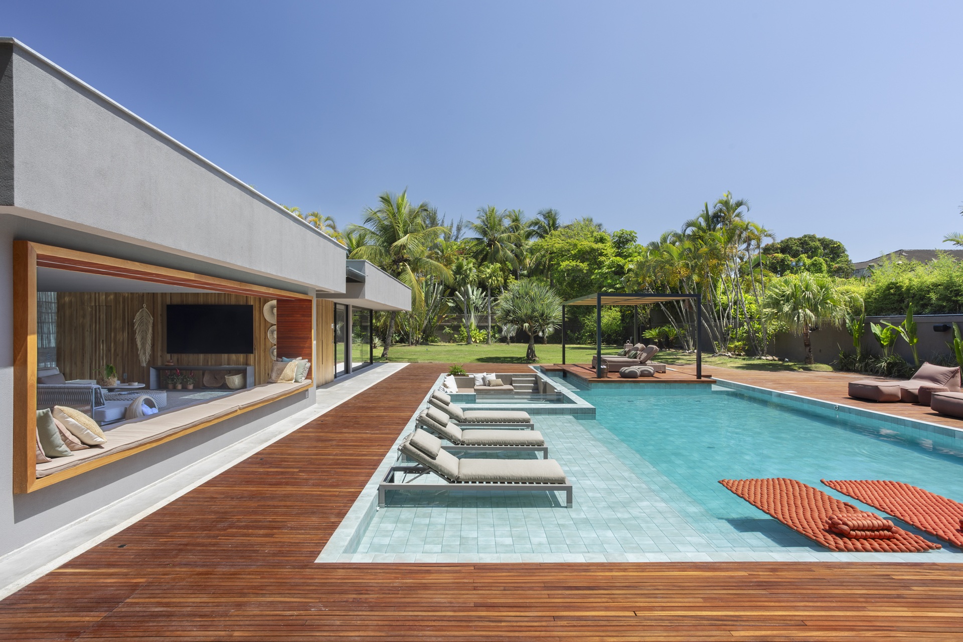 Quintal amplo com piscina e vasta área verde com árvores coladas no muro