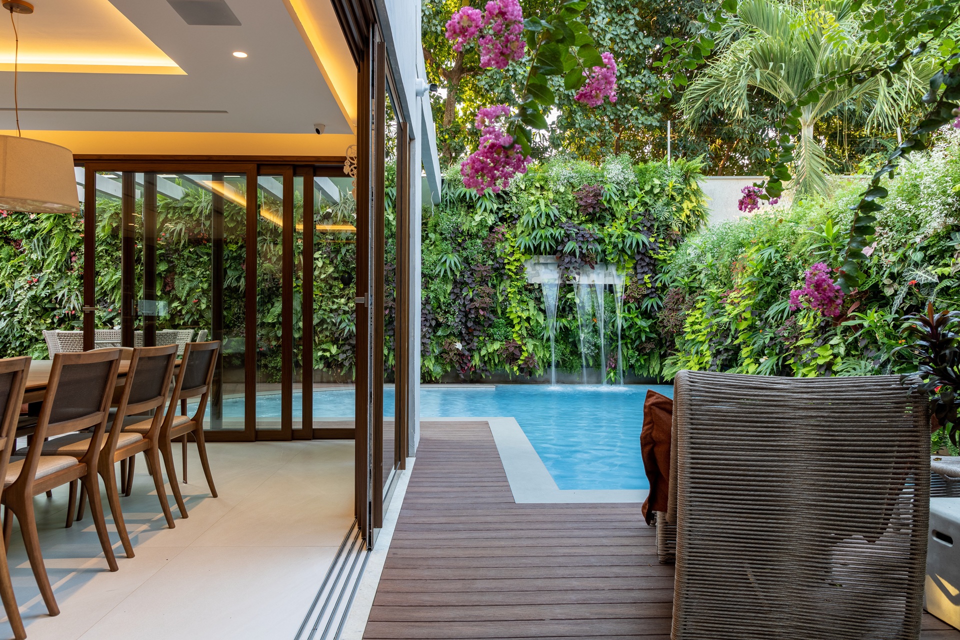 Área externa com deck de madeira e muro com jardim vertical
