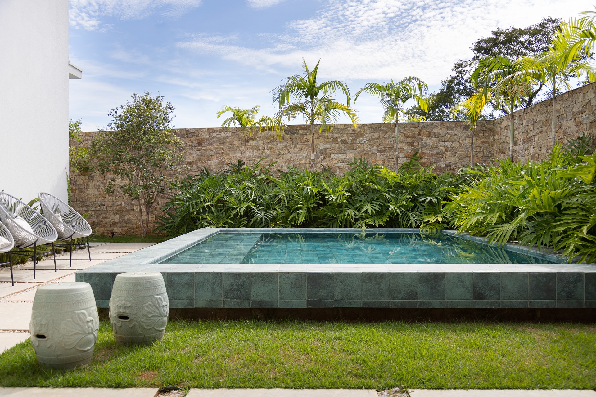 Quintal com piscina elevada em alvenaria e paisagismo no entorno