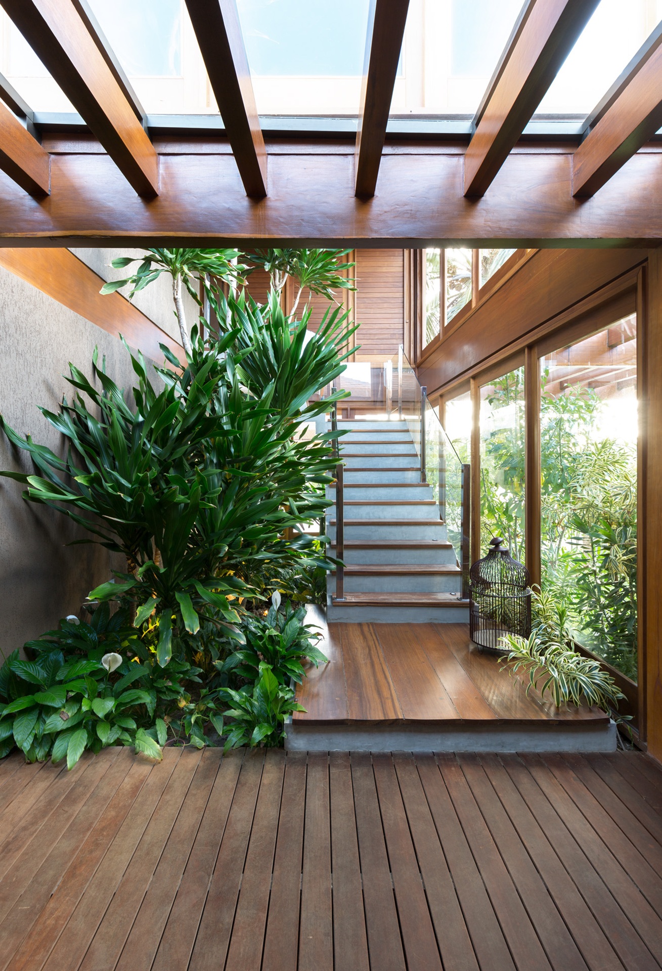Espaço externo de uma casa projetado como interno com plantas do lado da escada