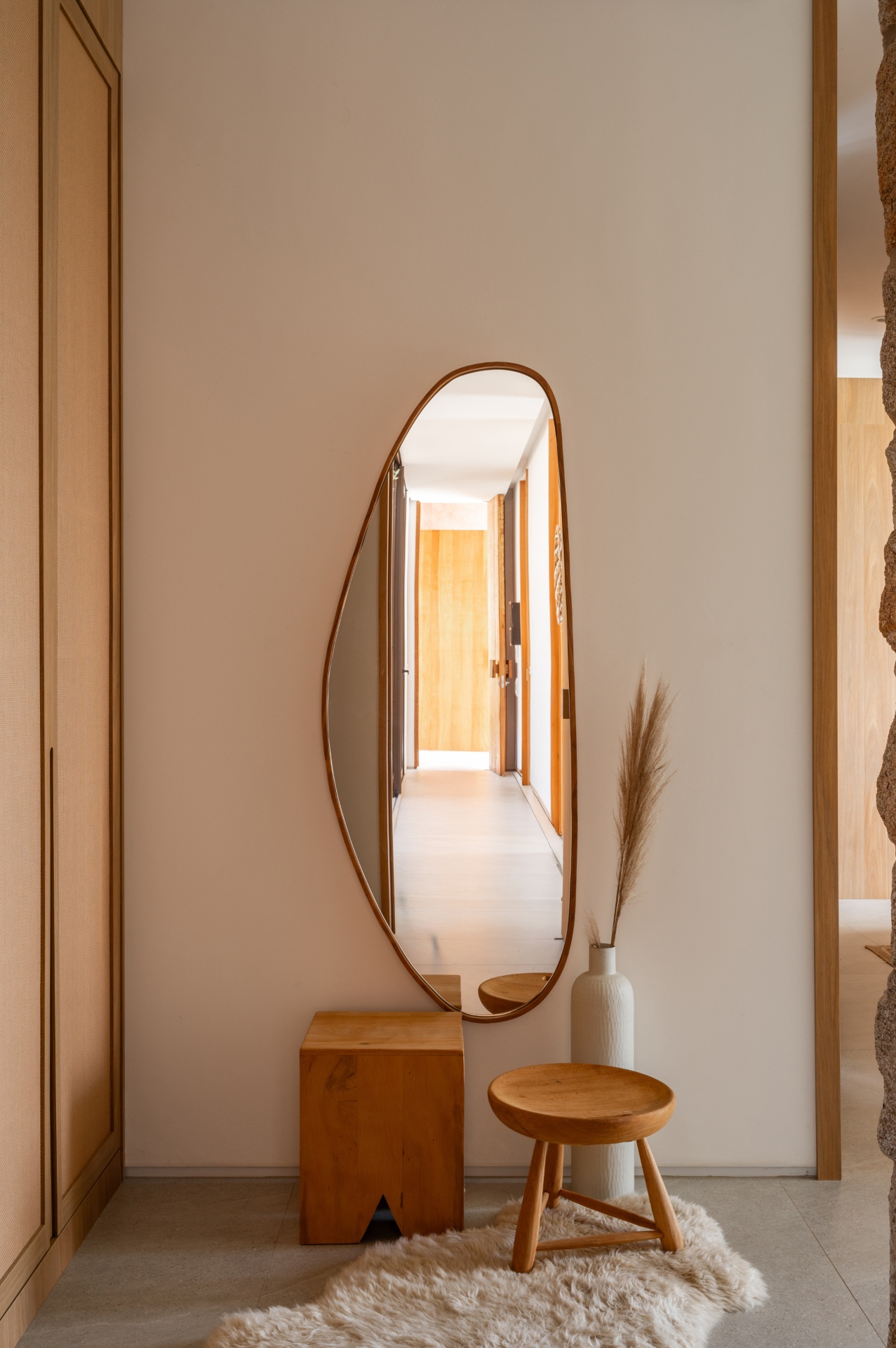 Cantinho do quarto com espelho e pontos de madeira. Design limpo, com iluminação suave e poucos objetos