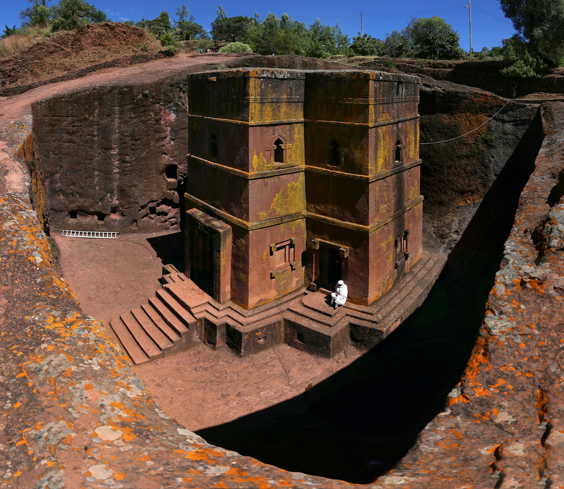igrejas pelo mundo Vista aérea da Igreja de São Jorge, em Lalibela, Etiópia — escavada diretamente na rocha vulcânica em forma de cruz, cercada por uma vala profunda e acessada por escadarias.