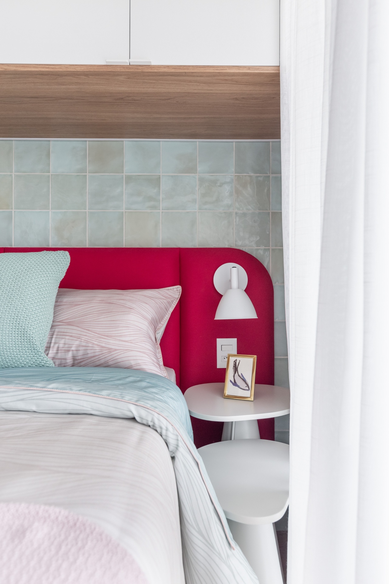 Detalhe de cabeceira de cama vermelha e revestimento suave na parede