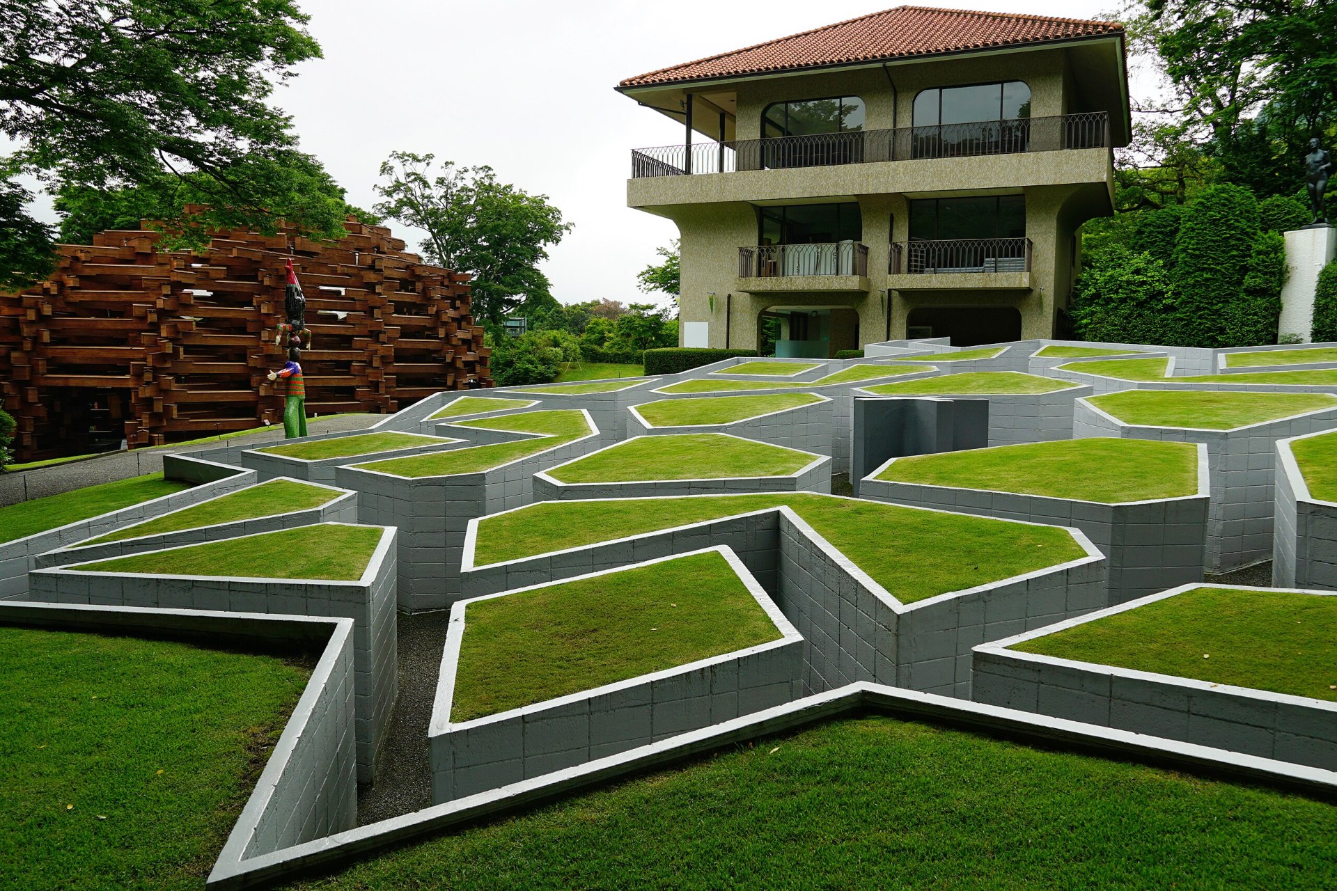 Em frente a uma casa, há um jardim com corredores profundos que geram formas geométricas