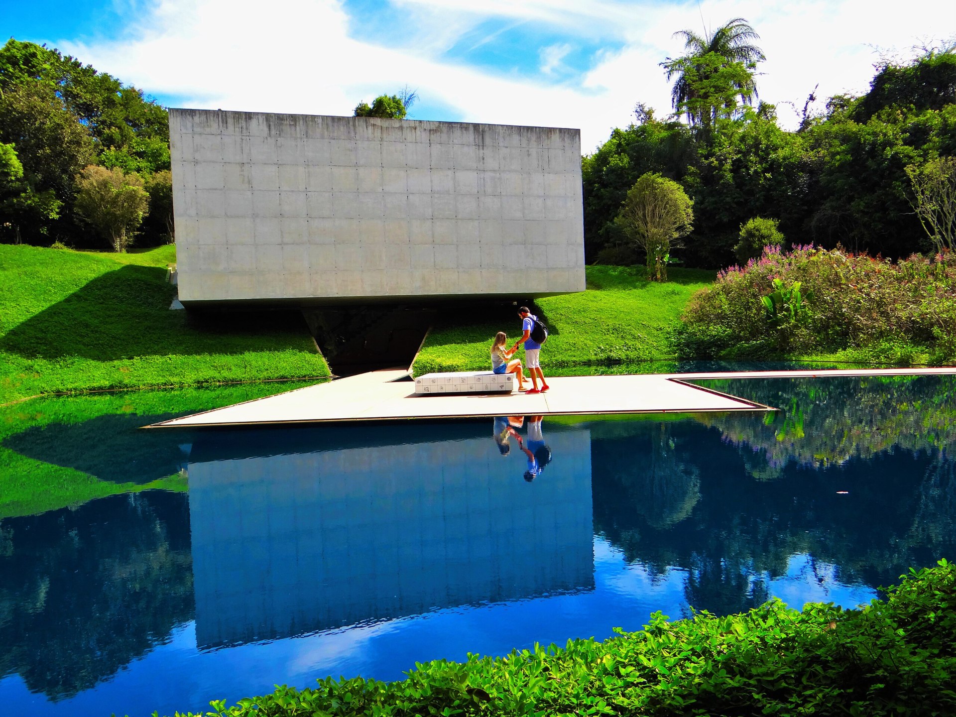 Galeria de arte refletida no lago à frente, rodeada de um belo paisagismo
