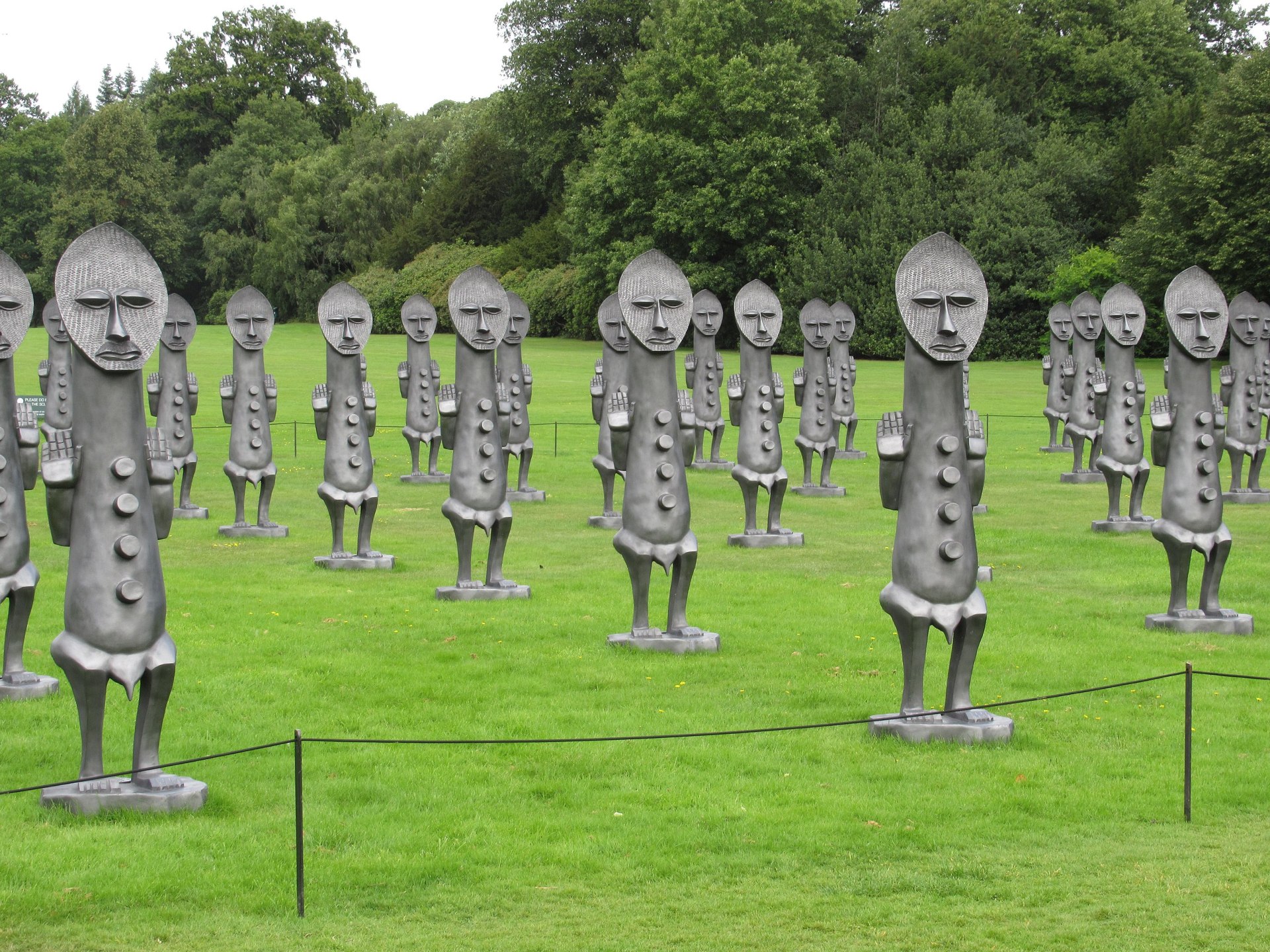 Esculturas de grandes figuras humanas em metal espalhadas por um gramado