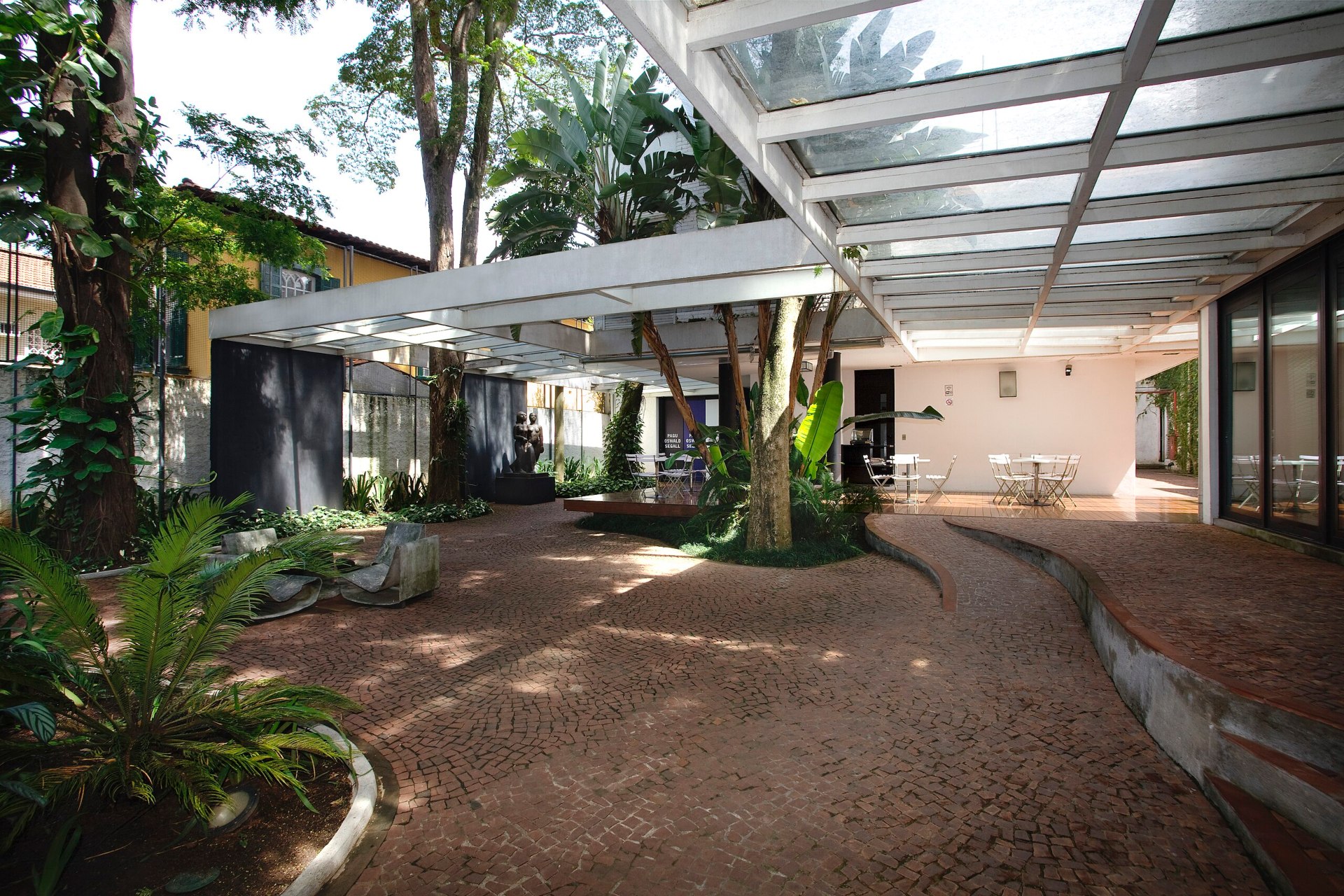 Parte externa do Museu Lagar Segall, com plantas, mesas e cadeiras