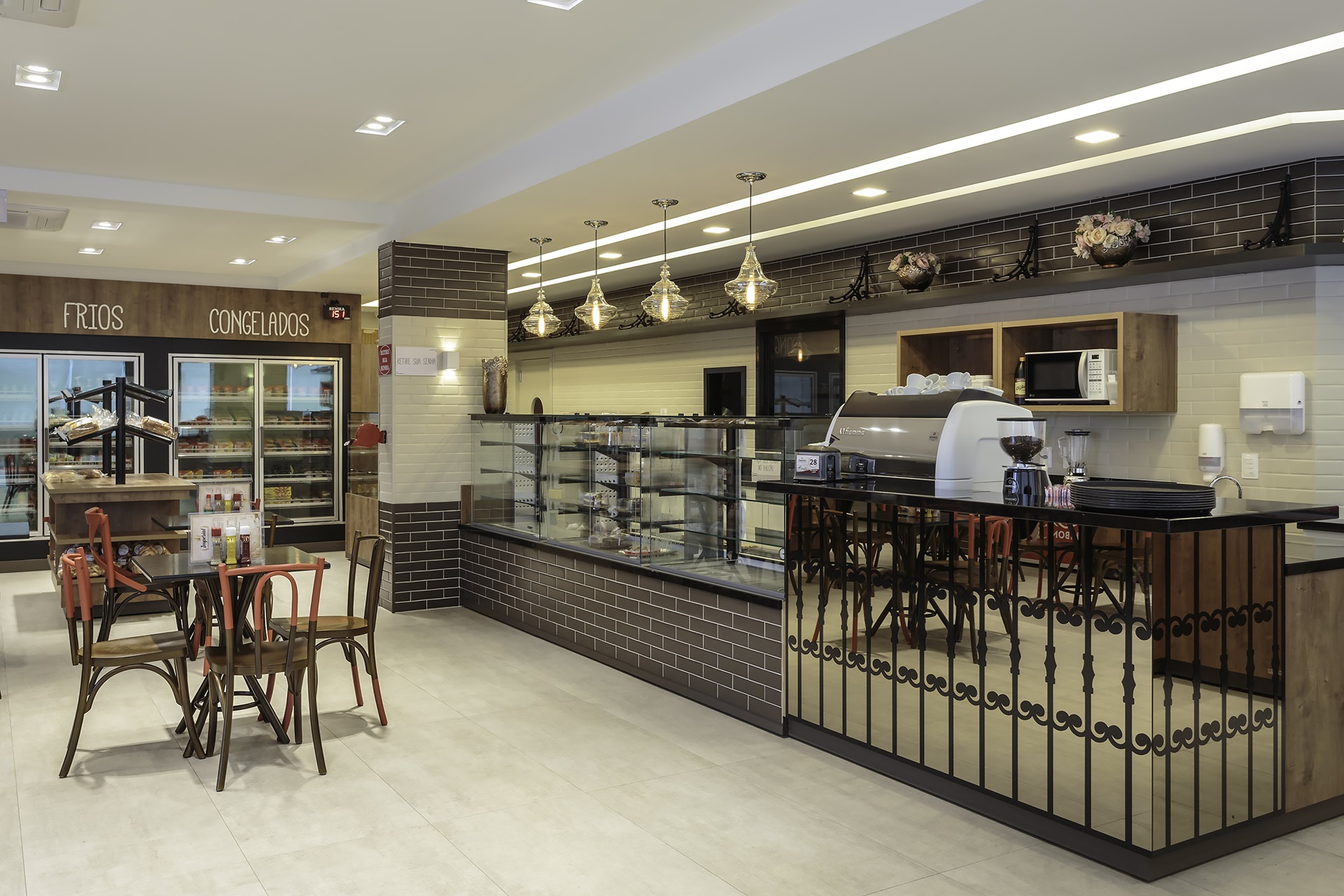 Padaria gourmet com mesa e cadeiras à esquerda e balcão de cafeteria à direita