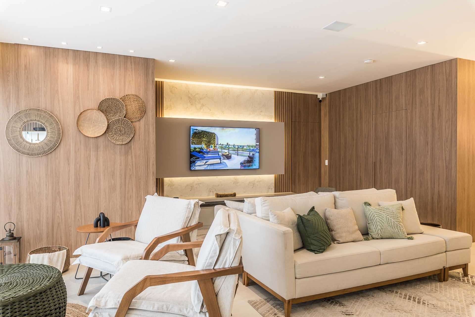 Living com paredes amadeiras e móveis claros, com televisão ao fundo
