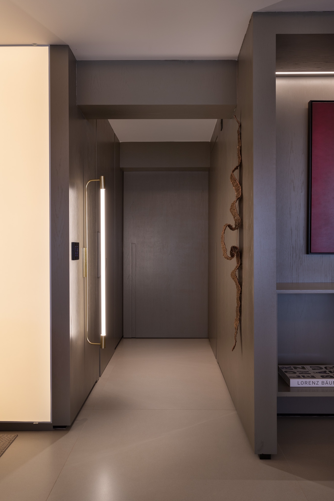 Hall de entrada monocromático com lâmpada vertical de led e escultura orgânica
