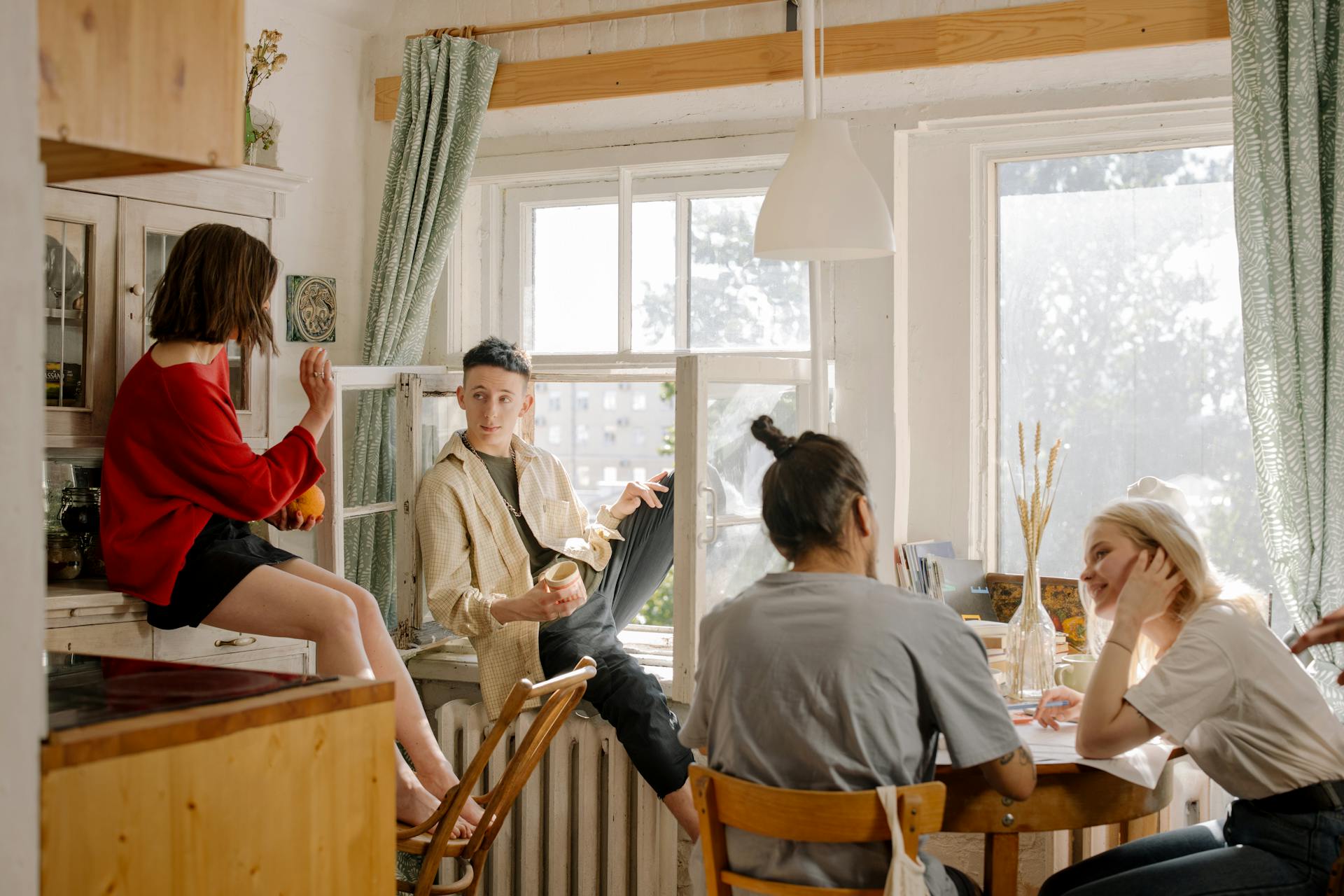 Coliving Quatro pessoas, dois homens e duas mulheres, convivendo em uma cozinha