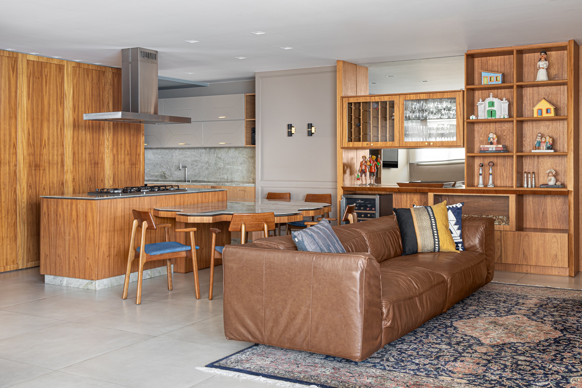 sala e cozinha integradas com estante, mesa e bancada de madeira e sofá marrom
