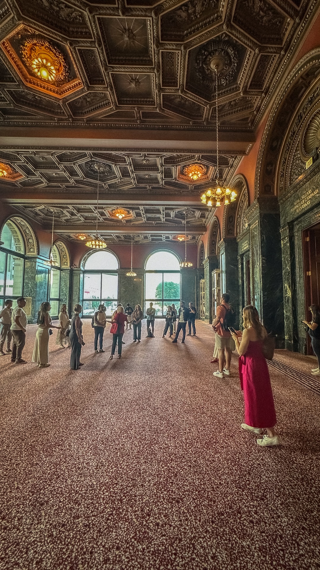 Imagem de salão em tons de vermelho e janelas amplas no Chicago Cultural Center