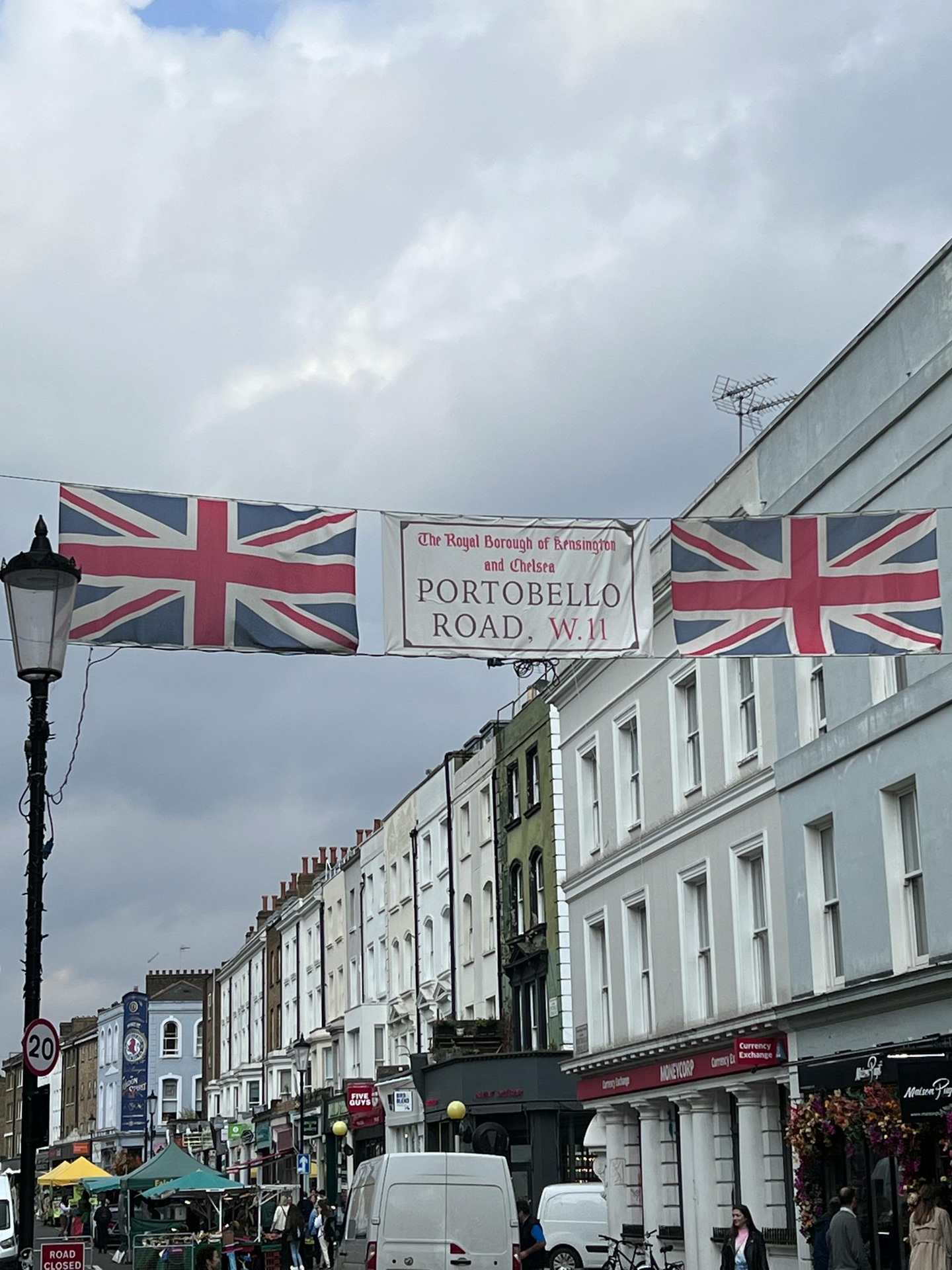 Faixa com o nome Portobello Road sob bandeiras britânicas decora a rua movimentada